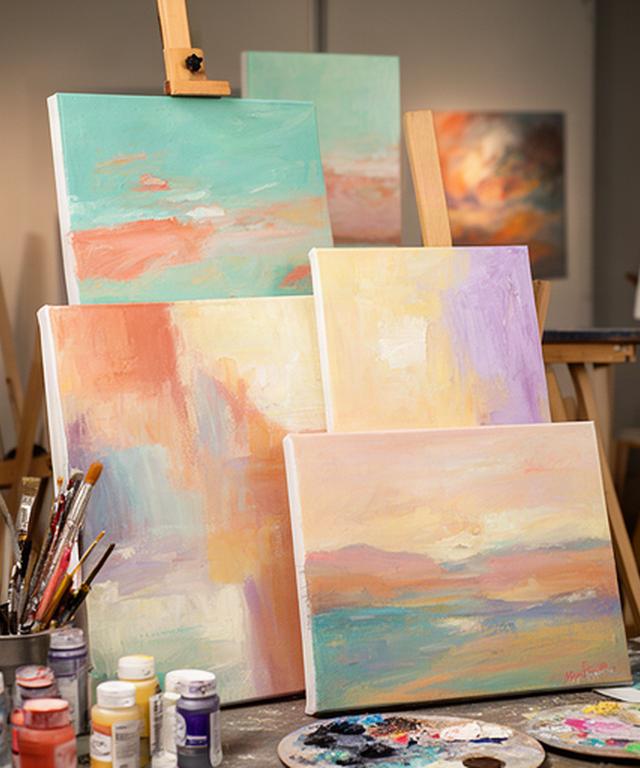 Finished pastel paintings propped against easels after a paint and sip night